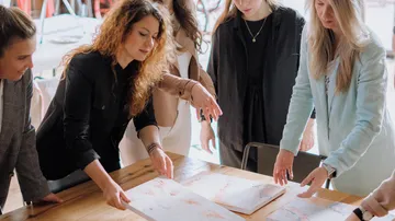 Women look at papers together on a table.