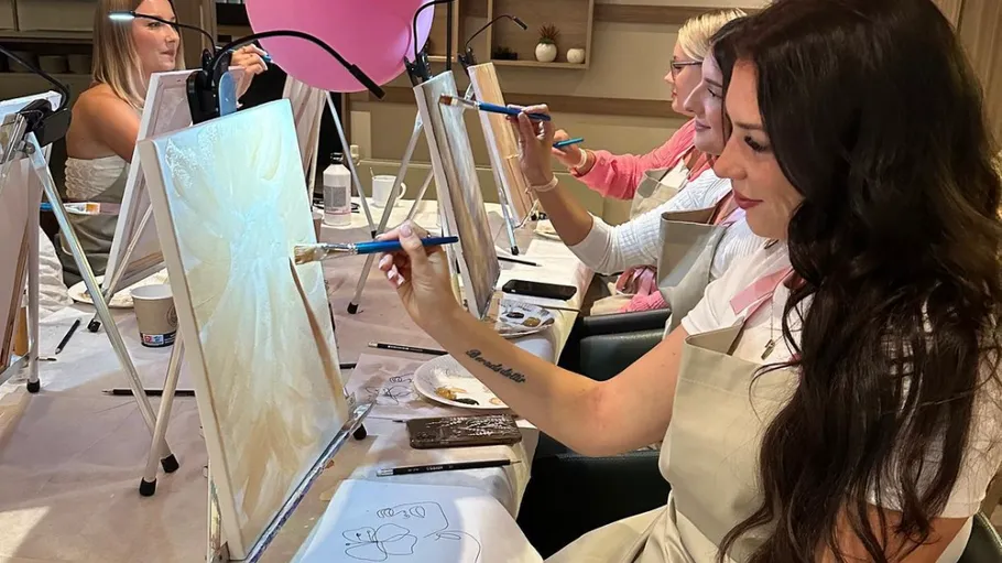 Women painting on canvases in art class.