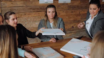 Frauen übergeben Kunstwerke in einem Besprechungsraum.