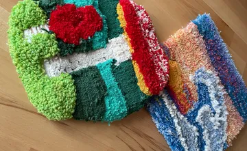 Bunte Teppiche liegen auf einem Holztisch.