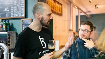 Mann spricht mit Glas, während ein anderer aufmerksam zuhört.