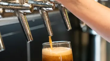 Ein Glas wird mit Bier aus einem Zapfhahn gefüllt.