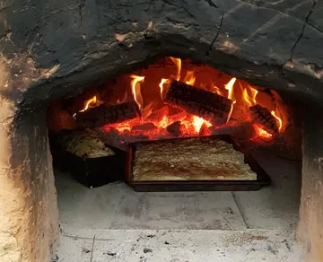Wood oven with burning fire and baking food.