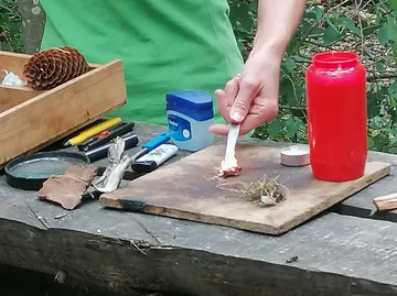 Eine Person zündet einen Stoffstreifen an einem Tisch an.