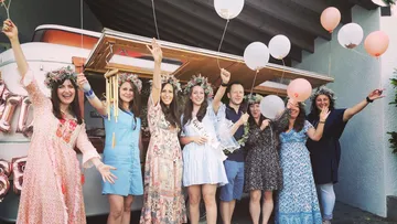Frauen mit Blumenkränzen feiern fröhlich mit Luftballons.