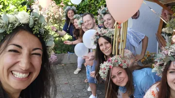 Eine Gruppe lächelnder Menschen mit Blumenkränzen posiert fröhlich.