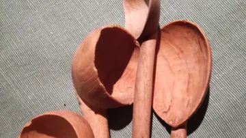 Holzlöffel liegen auf einem grauen Stoff, alles rustikal.