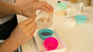 A hand pours liquid into a bowl on a table.