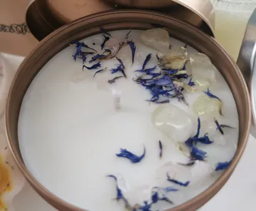 Candle with wax, flowers and crystals in a tin