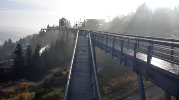 Wooden walkway connects a viewpoint with surrounding nature in fog.