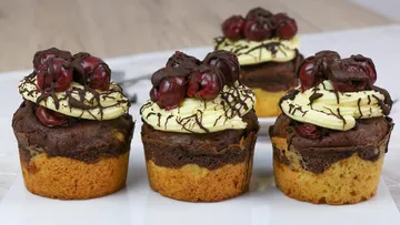 Schokoladenkuchen mit Sahne und Kirschen auf einem Tisch.