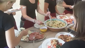 A group of women serve food at the table.