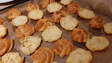 Kekse liegen gebacken auf einem Backblech mit Papier.