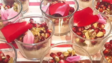 Desserts in Gläsern, dekoriert mit Granatapfel und Blütenblättern.