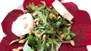 Rote-Bete-Scheiben umgeben frische Arugula mit Ziegenkäse.