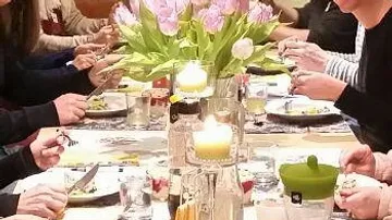 Tischgemeinschaft mit Essen, Kerzen und Frühlingsblumen dekoriert.