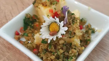 Kleine Schüssel mit dekoriertem Gericht aus Kräutern und Blume.