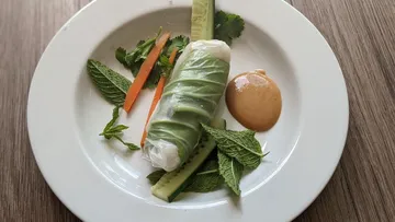 Rice roll is placed on a plate surrounded by fresh vegetables.