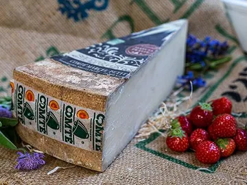 Käse liegt auf einer Jutesack-Oberfläche mit Erdbeeren.
