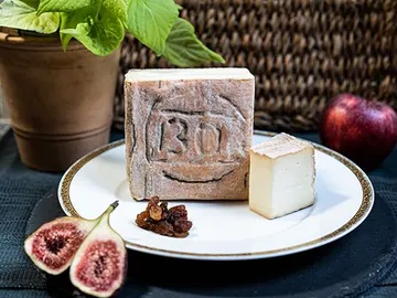 Käse auf Teller, umgeben von Feigen und Obst.