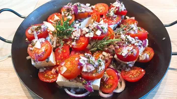 Plate with tomatoes, onions and herbs prepared for cooking.