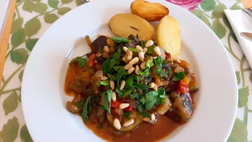 Mix of vegetables with herbs and pine nuts on the plate.