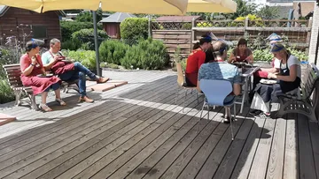 People eat together on a sunny terrace.