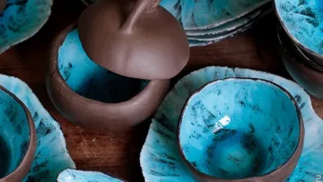 Braune Schalen mit blauer Innenfarbe liegen auf Holz.