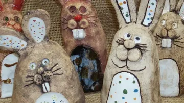 Bunte Hasenfiguren stehen vor einem Jutehintergrund.
