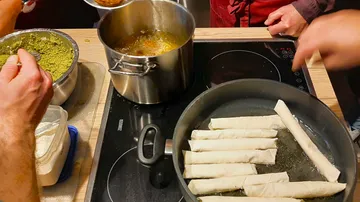 Fried dough rolls are prepared in a pan.