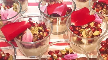 Desserts in Gläsern, dekoriert mit Granatapfel und Blütenblättern.