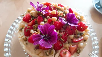 A cake with strawberries and flowers on a plate.