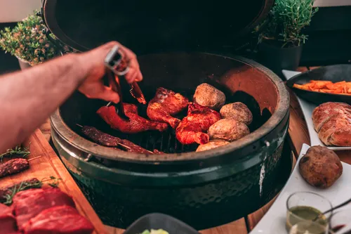 Hand grilling meat and potatoes in oven.
