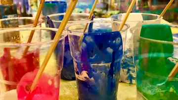 Mugs with bright colors and sticks stand side by side.