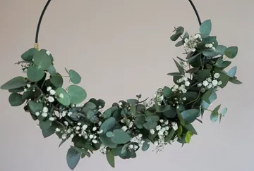 Circular wreath of eucalyptus and white flowers hangs.
