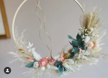 Circular wreath with dried flowers hangs in a room.