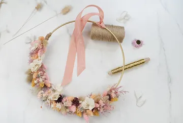Wreath of flowers on table surrounded by craft materials.