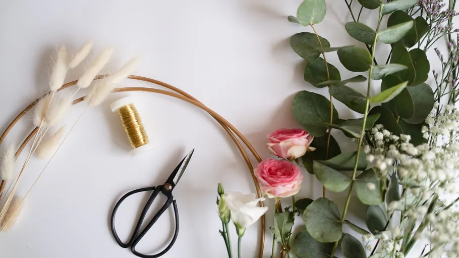 Schneider greifen Blumen, erstellen florale Kunst auf Tisch.