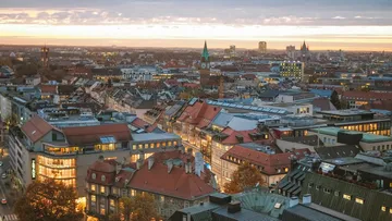 City view at sunset, rooftops glow warm and orange.
