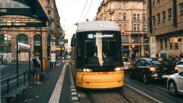 Tram goes to the stop in an urban area.