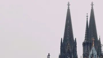 Zwei hohe gotische Türme ragen in den grauen Himmel.