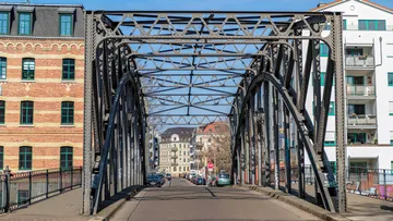Eisenbrücke über eine Straße, umgeben von Gebäuden.
