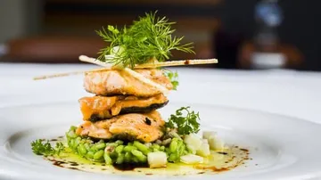 Salmon on green risotto decorated with herbs.
