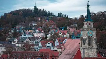 The church tower stands between colorful houses in autumn.