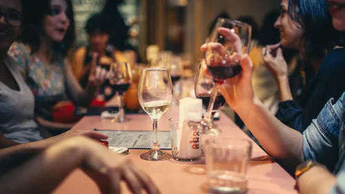 Wine glasses on a table surrounded by people partying