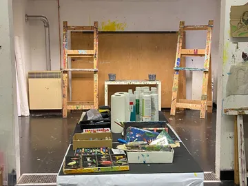 There is a table with painting supplies in a studio.