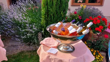 Silver bowl contains wine bottles surrounded by flowers
