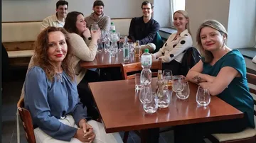 Eight people sit at a table in a restaurant.