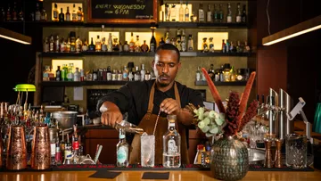 Bartender bereitet Cocktails an einer gut sortierten Bar.