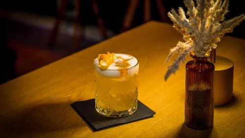 Drink on table, with blossoms nearby.